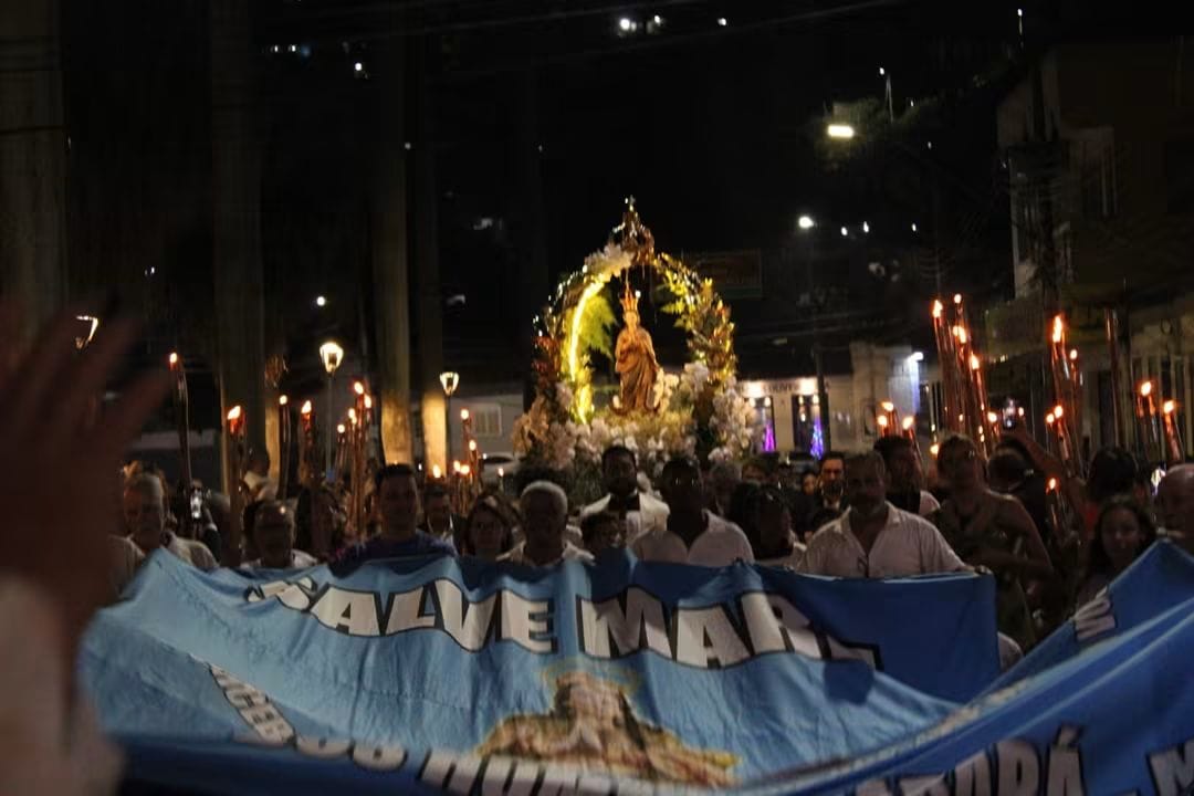 Fiéis e estandarte mariano em procissão noturna